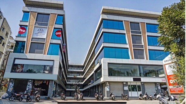 A modern hotel with a central courtyard, multiple floors, and a mix of glass and concrete facades. - Hotel Santeria Inn (Surat)