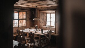 A rustic wooden dining room with a large table, chairs, and a hanging light fixture.