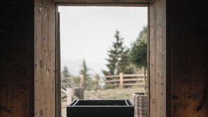A wooden-framed window with a view of a fenced outdoor area and a wicker basket.