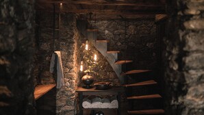 A rustic stone staircase with wooden steps and a hanging light fixture.
