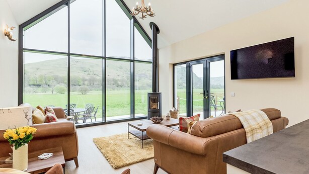 A spacious living room with large windows, a fireplace, and a flat-screen TV. - Balbeg Cottage by Interhome (Ayr)