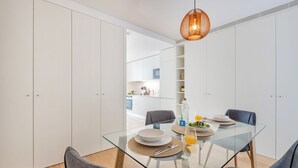 Un comedor moderno con una mesa de vidrio, sillas grises y una lámpara colgante.