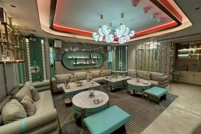 A modern lounge area with sofas, tables, and a bar.