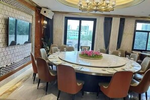 Une salle de conférence équipée d’une table ronde, de chaises, d’un téléviseur et d’une grande fenêtre donnant sur la ville.