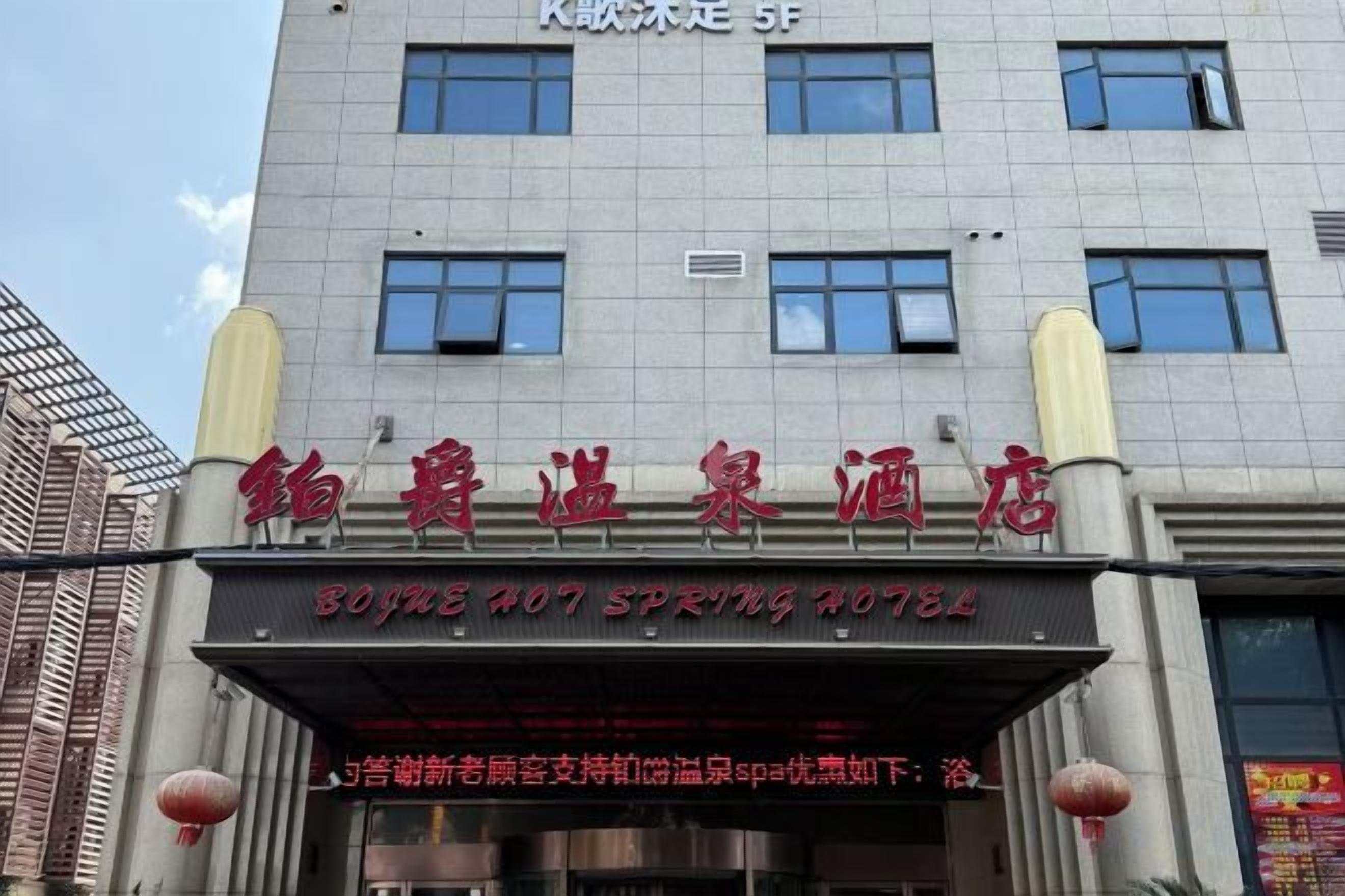 A hotel with a sign in a foreign language, multiple windows, and a digital display at the entrance.