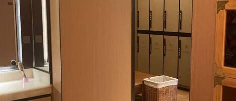 A hotel room with a wooden door, a sink, and a set of cabinets.