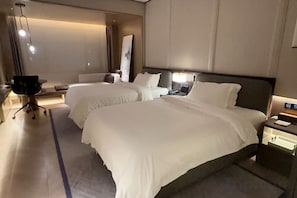 A hotel room with two beds, a desk, a chair, and a nightstand with a lamp. - Shanghai Grand Hotel (Shanghai)