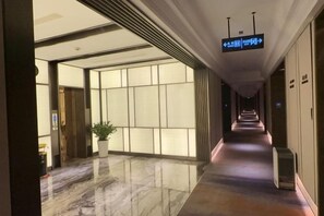 A hotel corridor with directional signs, a potted plant, and a polished floor. - Shanghai Grand Hotel (Shanghai)