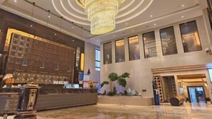 A hotel lobby with a large chandelier, a reception desk, and a seating area with plants. - Shanghai Grand Hotel (Shanghai)