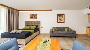 Une chambre d’hôtel avec un lit, un canapé, une table basse et deux tableaux au mur.