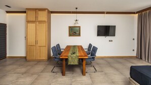 Une pièce comprenant une table à manger en bois, six chaises, un téléviseur fixé au mur et une grande armoire.