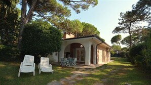 A house with a covered patio and outdoor seating area. - Lovely Villa Surrounded by Greenery in Lignano Riviera (Lignano Sabbiadoro)