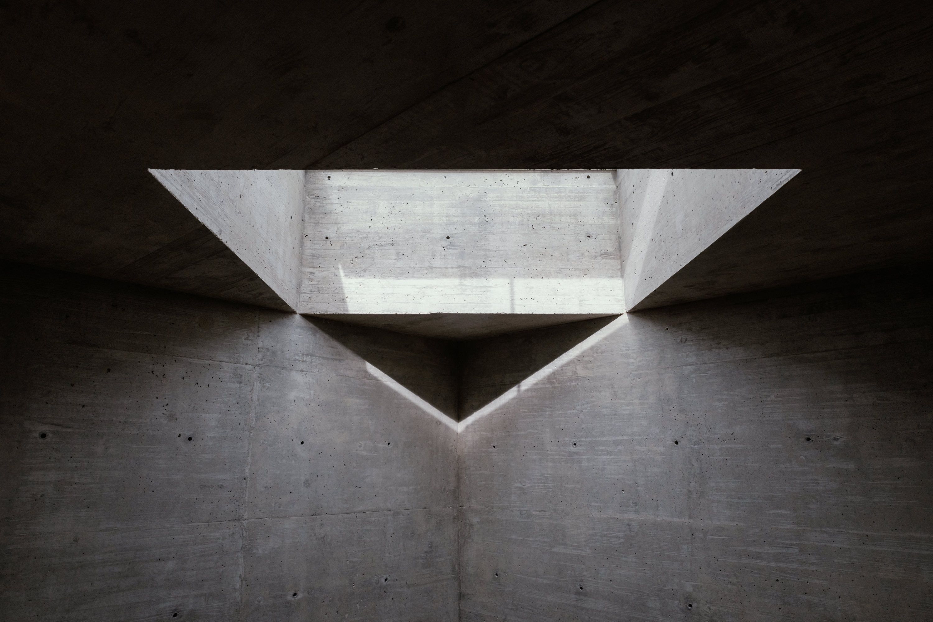 A concrete interior with a triangular skylight.