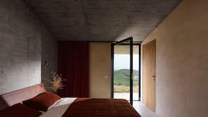A bedroom with a bed, a window, and a view of a landscape. - Villa Esovisia by Elite Villas (Avola)