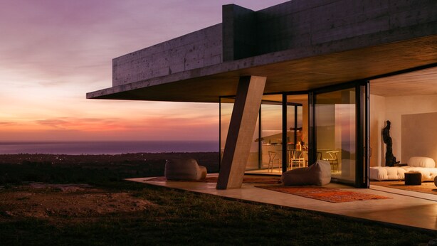 A modern house with a large glass door, a dining area, and a view of the landscape. - Villa Esovisia by Elite Villas (Avola)