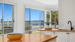 Una cocina moderna con amplios ventanales, encimera de madera y vistas a un lago.