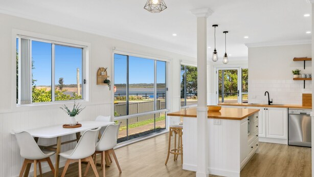 Una cocina moderna con ventanales amplios, un comedor con vistas y un interior limpio y blanco.