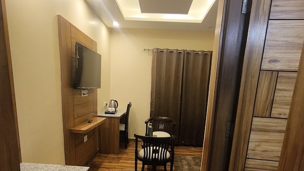 A compact living space with a kitchenette, a dining area, and a TV mounted on the wall. - Virat Hills by Blue Waves (Mussoorie)