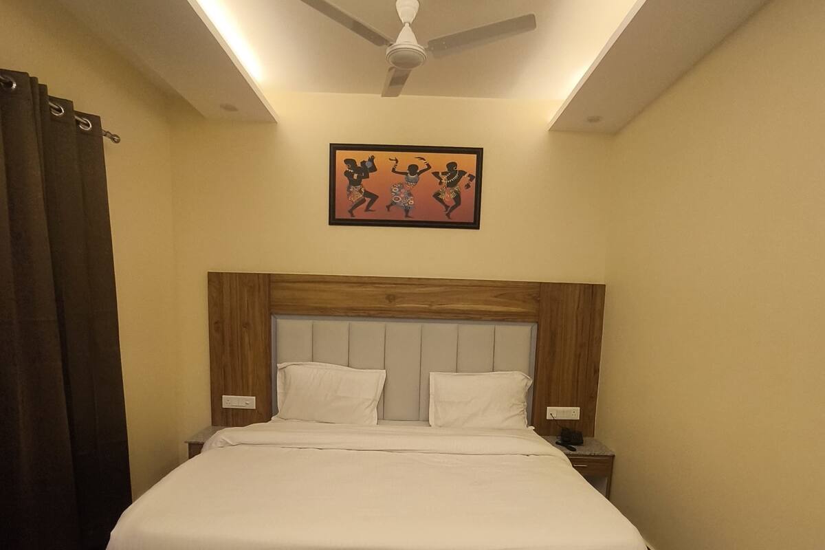 A neatly made bed with a wooden headboard, a ceiling fan, and a framed picture above it.