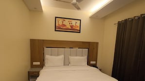 A bedroom with a bed, a ceiling fan, a nightstand, a chair, and a picture on the wall. - Virat Hills by Blue Waves (Mussoorie)