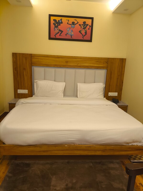 A neatly made bed with white linens, a wooden headboard, and two bedside tables with lamps.