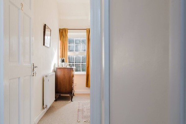 A hallway with a radiator, a wooden dresser, and a window with curtains. - Idyllic Foodie Retreat above Silks Pub (Marlborough)