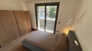 Une chambre à coucher comprenant un lit, une armoire, une porte-fenêtre coulissante et une lampe de chevet.