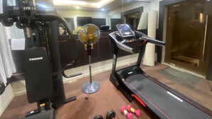 Una palestra con tapis roulant, pesi e un ventilatore.