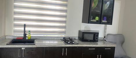 A kitchen with a granite countertop, a built-in microwave, a gas stove, and a cabinet with a glass door.