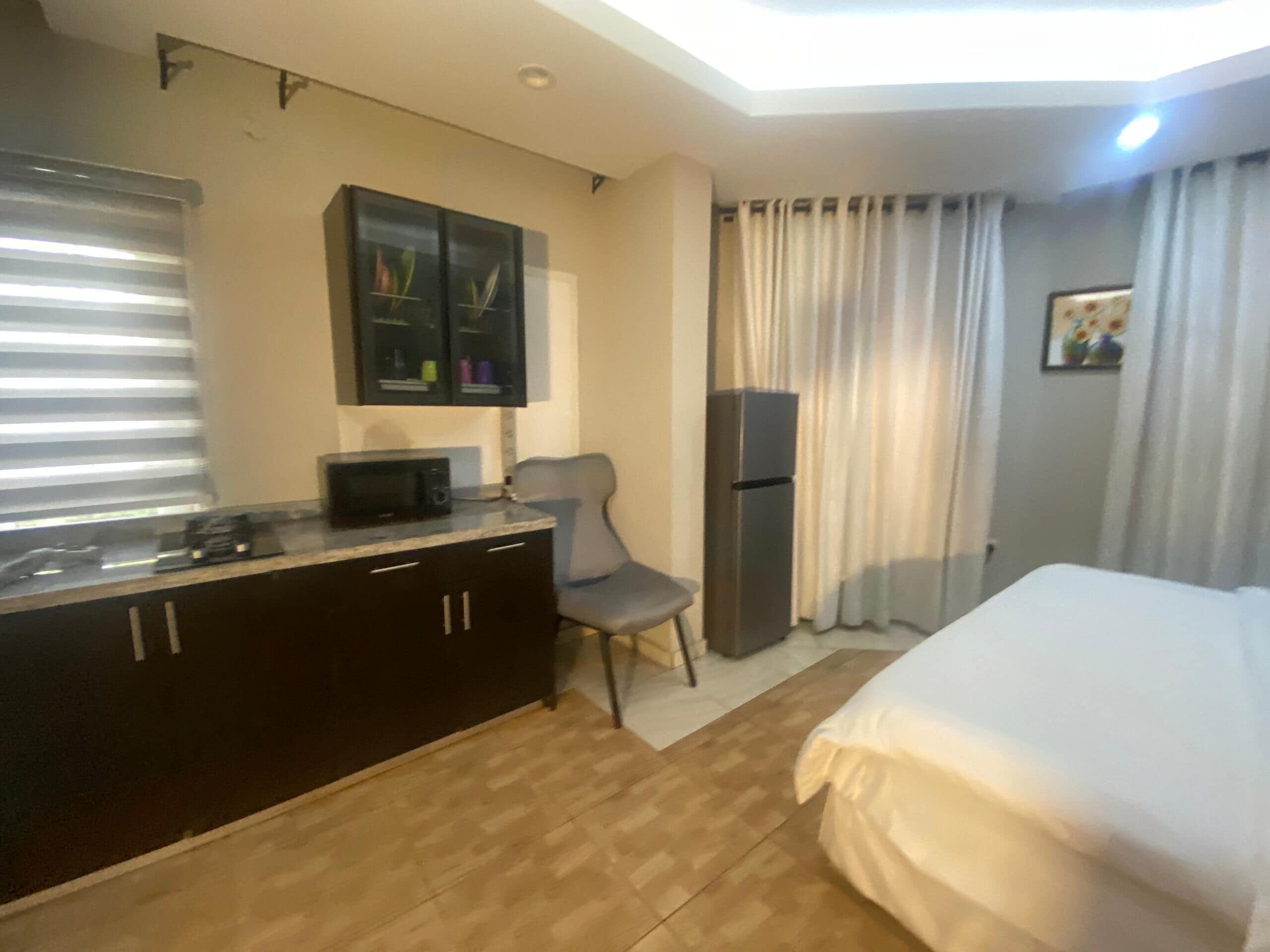 Ein Hotelzimmer mit einem Bett, einem Schreibtisch, einer Mikrowelle, einem Kühlschrank und einem Sessel.