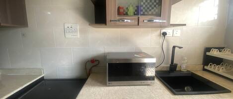 A kitchen with a stove, microwave, sink, and cabinets.