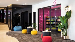 Een modern interieur met een golvend tapijt, kleurrijke zitplaatsen, een gemakswinkel en een trap.