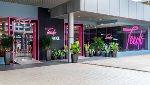 Een modern gebouw met een opvallend 'Teedo' neonbord in roze.
