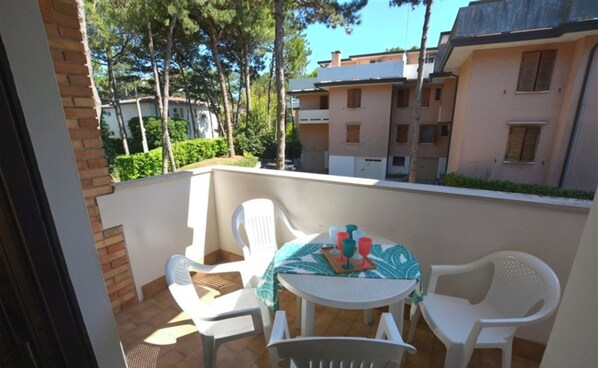 A balcony with a table and chairs, overlooking a residential area with apartment buildings. - Comfortable Flat With Balcony for Nine Guests in Lignano Sabbiadoro (Lignano Sabbiadoro)