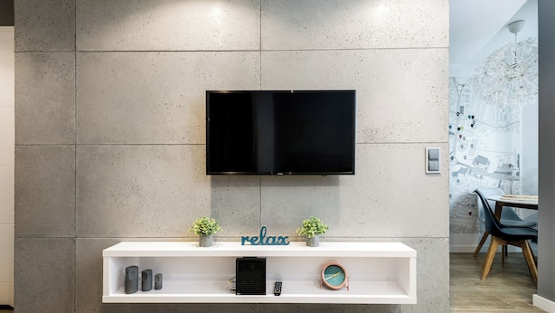 A modern living room with a flat-screen TV mounted on a textured wall, a white console table with decorative items, and a dining area in the background. - Apartament Spodek - by Kairos Apartments (Katowice)