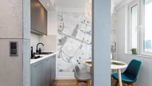 A modern kitchen with a map mural, a dining area with a round table and chairs, and a window with a view. - Apartament Spodek - by Kairos Apartments (Katowice)