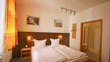 Ein Hotelzimmer mit einem Bett, Nachttischen, einer Dusche und zwei Bildern an der Wand.