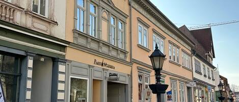 A street with historic buildings, a pension sign, and a lamp post.