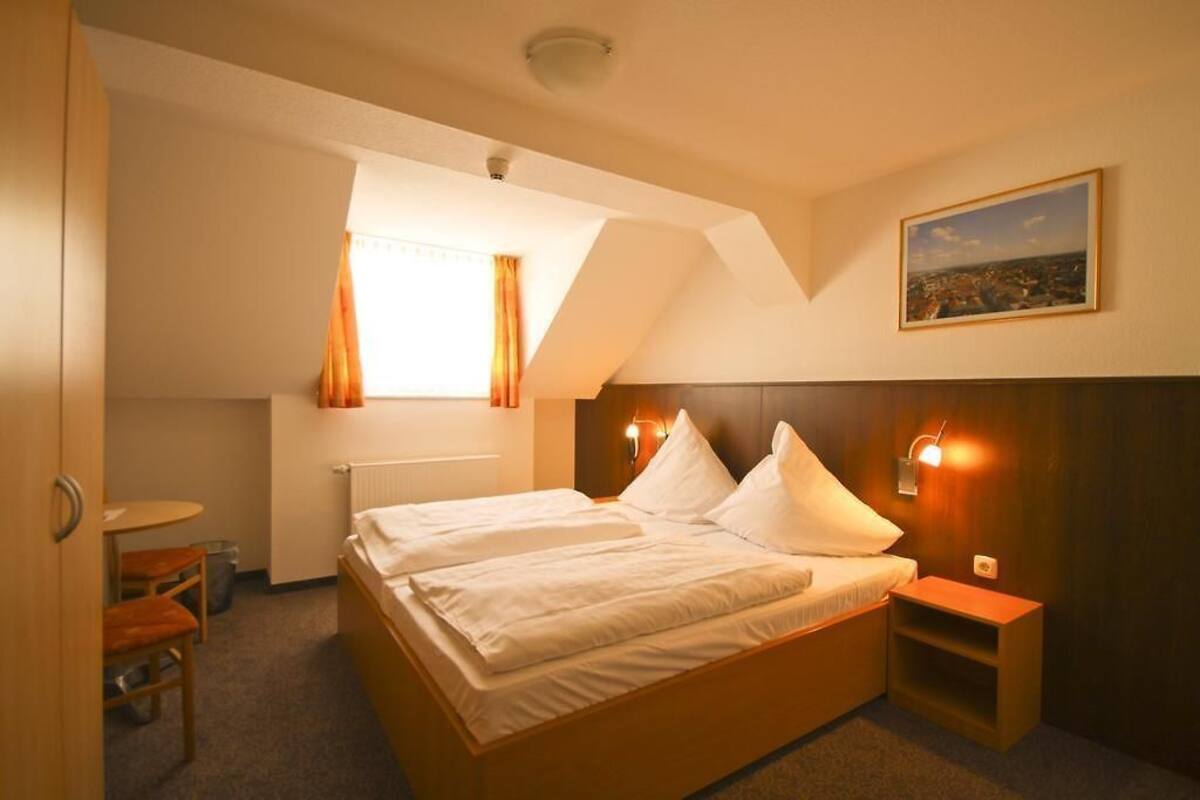 A hotel room with a bed, a small table, and a chair.