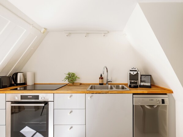 A compact kitchen with a wooden countertop, a Bosch dishwasher, a Bosch oven, and a sink. - Admiral - Cosy 1-bdr Apt in Central Copenhagen (Copenhagen)