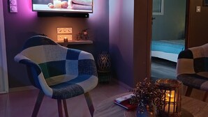 A modern living room with a flat-screen TV, a sofa, a coffee table, and decorative items.