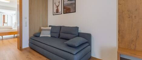 Una sala de estar moderna con un sofá gris, listones de madera y dos cuadros en la pared.