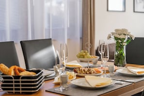 Enjoy a formal dining experience with a beautifully set table, complete with a selection of cheeses, grapes, and a decadent dessert.
