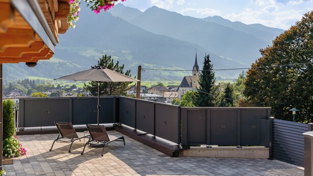 Ein Balkon mit Bergblick, einem Stuhl und einem Sonnenschirm.