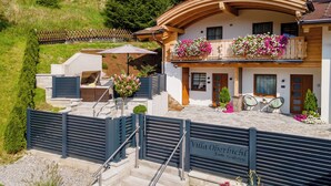 Eine Villa mit gewölbter Dachform, einem Balkon mit Blumenkästen und einer Steintreppe, die zum Eingang führt.
