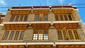 Un edificio de varios pisos con un estilo arquitectónico tradicional, con marcos de ventanas de madera y fachada de piedra.