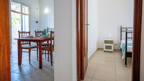 A room with a bed, bedside table, and a small table with chairs. - Residence degli Oleandri (Villanova)