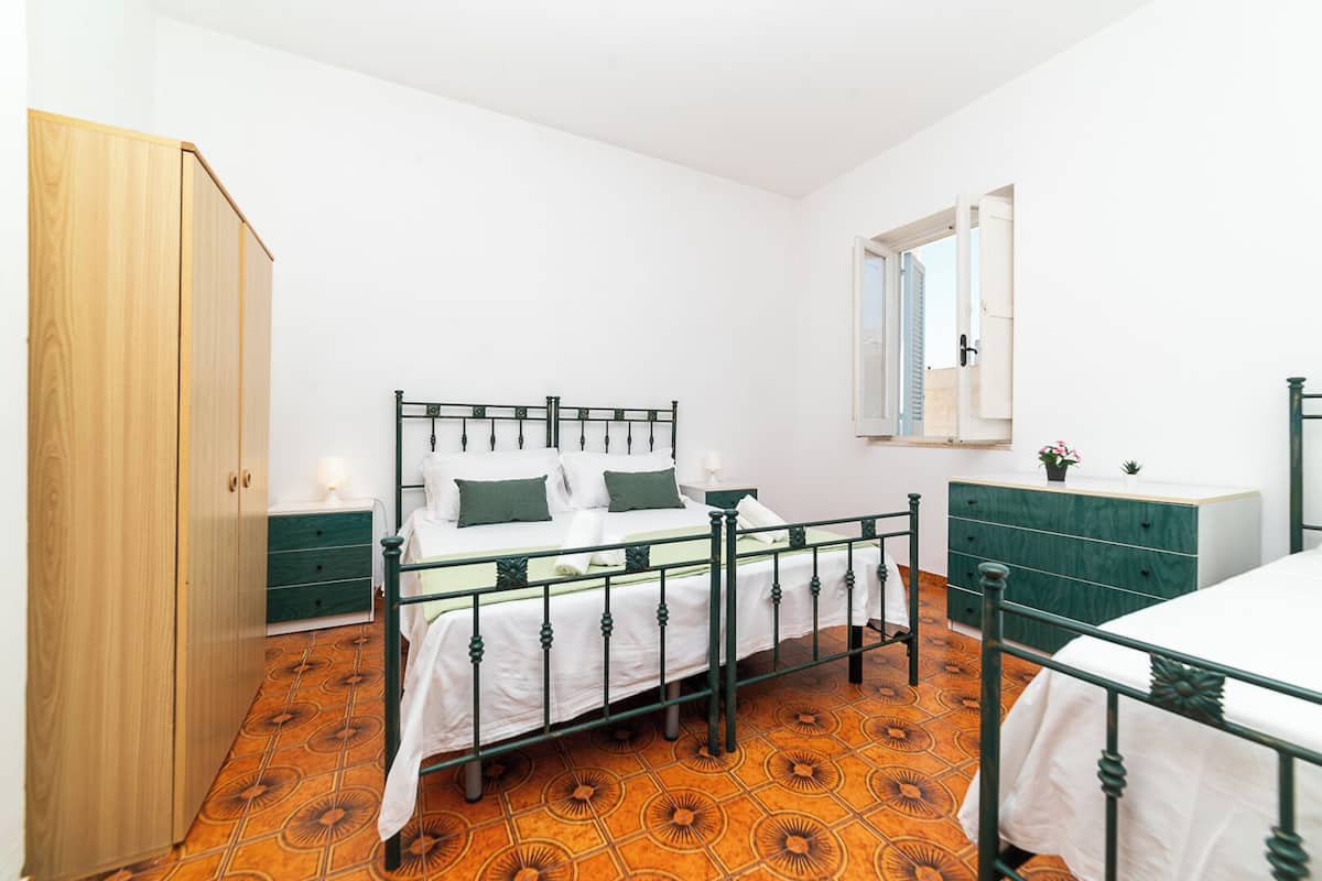 A bedroom with a bed, a dresser, a wardrobe, and a window.
