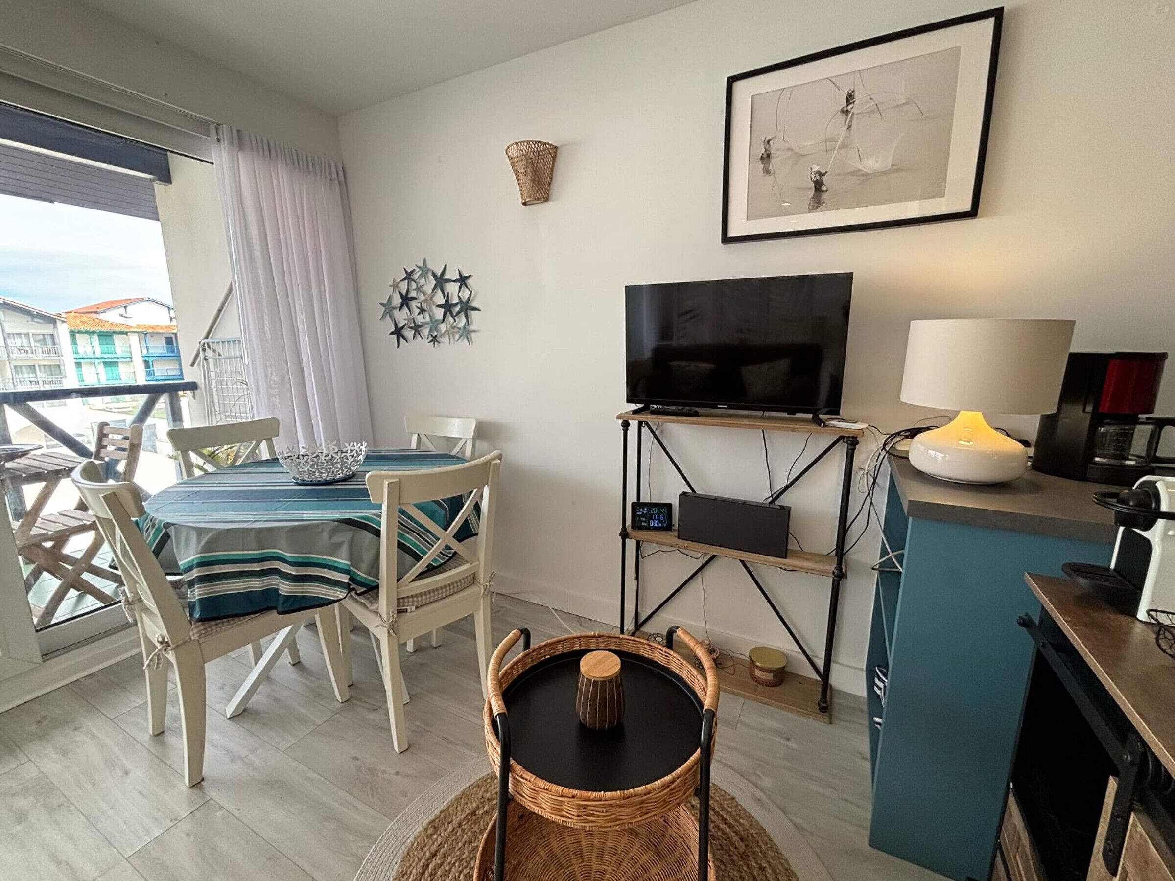 Un espace de vie compact comprenant un coin repas, un téléviseur, une lampe et une petite cuisine.