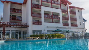 A multi-story hotel with a swimming pool in the foreground. - Charming 2-room apartment with pool in Hendaye, near port (Hendaye)